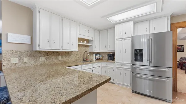 a kitchen with granite countertop white cabinets and stainless steel appliances