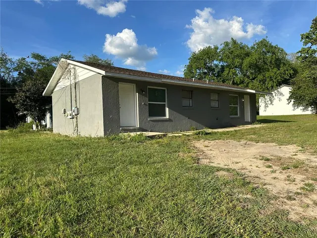 a front view of house with yard and trees in the background