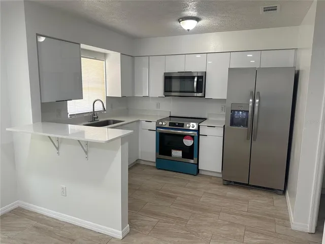 a kitchen with stainless steel appliances a refrigerator a sink a stove a microwave and cabinets