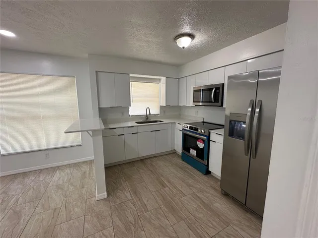 a kitchen with stainless steel appliances a refrigerator sink and microwave