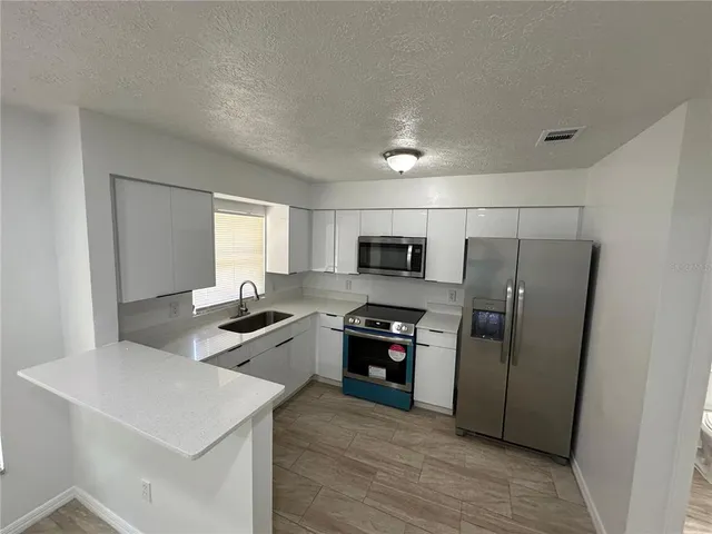 a kitchen with stainless steel appliances a stove a sink and a refrigerator