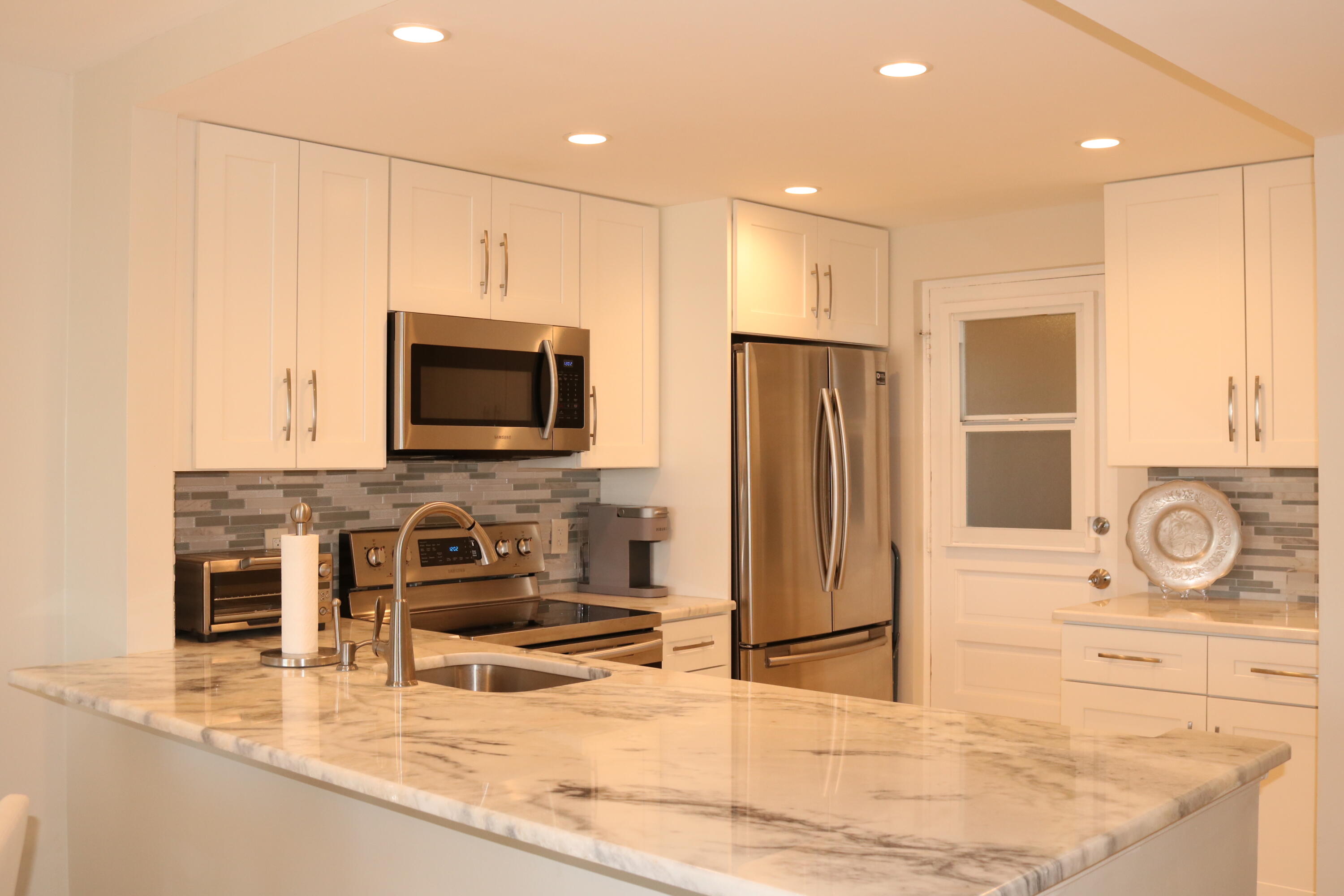 6461 Northwest 2nd Avenue, Unit 508 Boca Raton, FL 33487 - Photo 2 of 39 a kitchen with stainless steel appliances granite countertop a refrigerator a stove and a sink with wooden cabinets