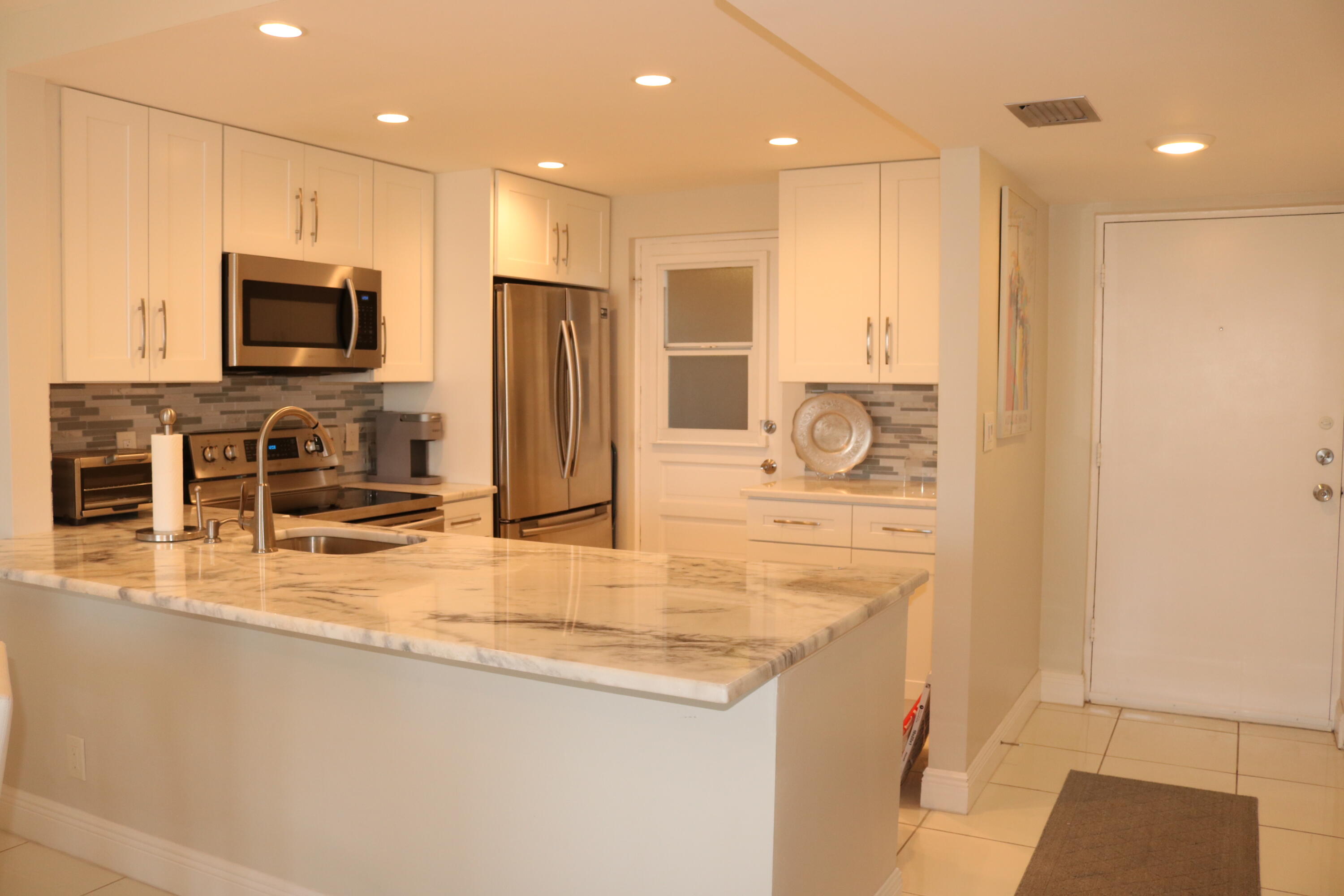 6461 Northwest 2nd Avenue, Unit 508 Boca Raton, FL 33487 - Photo 3 of 39 a kitchen with stainless steel appliances granite countertop a refrigerator a stove and a sink with wooden floor