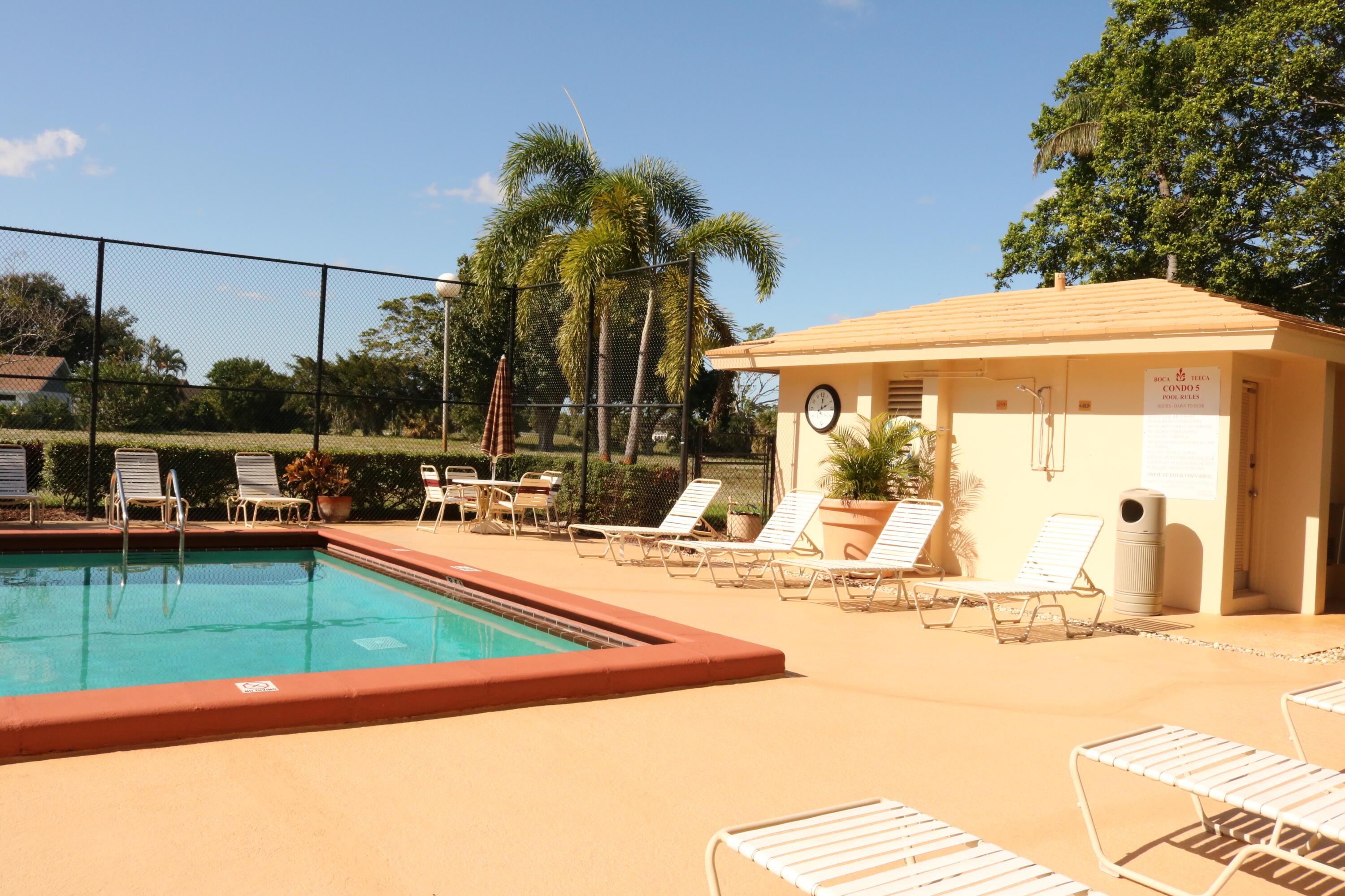 6461 Northwest 2nd Avenue, Unit 508 Boca Raton, FL 33487 - Photo 35 of 39 a view of a swimming pool with a lawn chairs under an umbrella