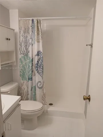 a white toilet sitting next to a shower curtain