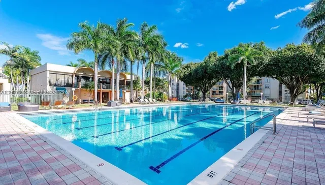 a view of a swimming pool with lawn chairs and plants
