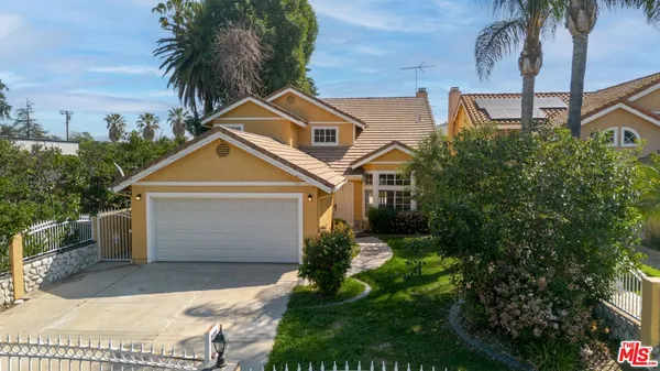a view of a white house with a small yard and plants