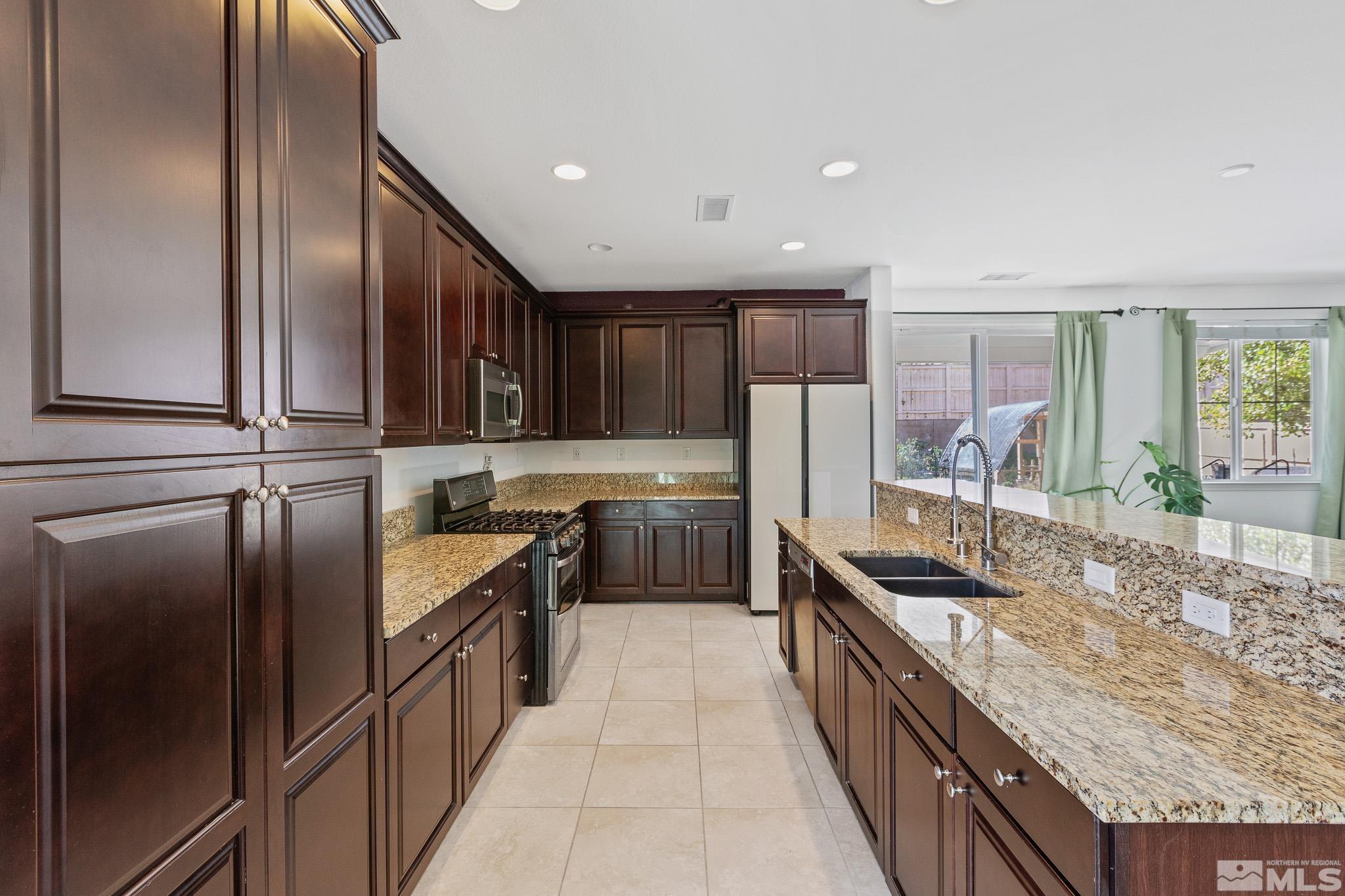 10579 Foxberry, Unit DRIVE Reno, NV 89521 - Photo 6 of 36 a kitchen with stainless steel appliances granite countertop a stove a sink and a refrigerator