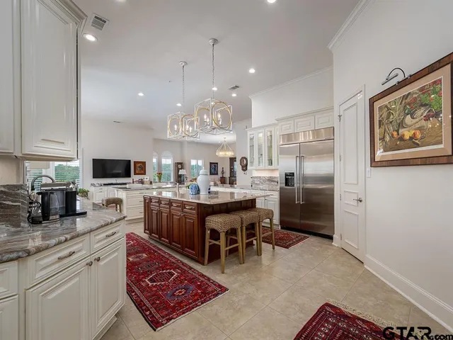 a kitchen with stainless steel appliances granite countertop a refrigerator a stove a sink a dining table and chairs with wooden floor