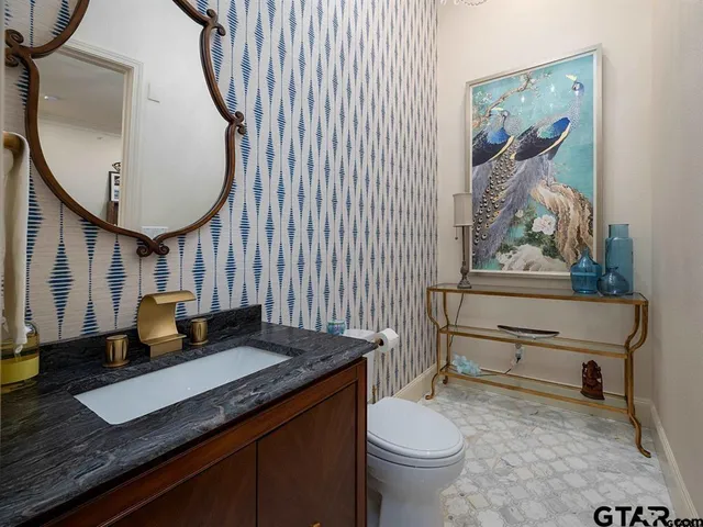 a bathroom with a granite countertop sink mirror vanity and toilet