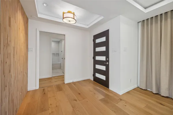 an empty room with wooden floor cabinet and windows