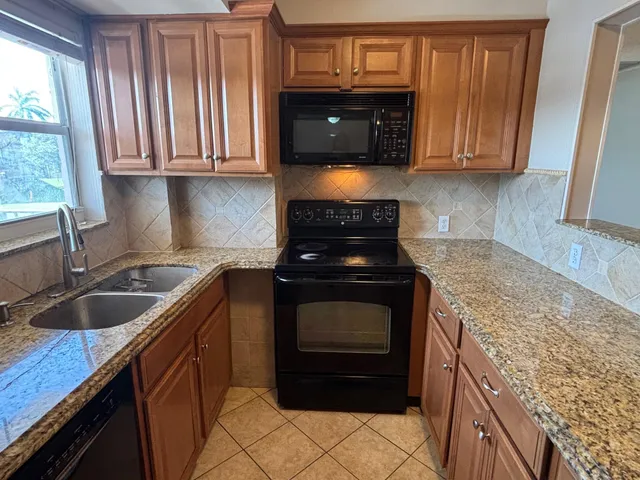 a kitchen with granite countertop stainless steel appliances stove microwave refrigerator and sink