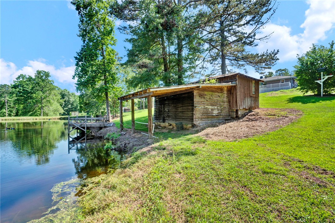7876 Highway 11 Walhalla, SC 29691 - Photo 4 of 35 A rustic barn and wooden dock overlook a serene pond, offering tranquil outdoor living.