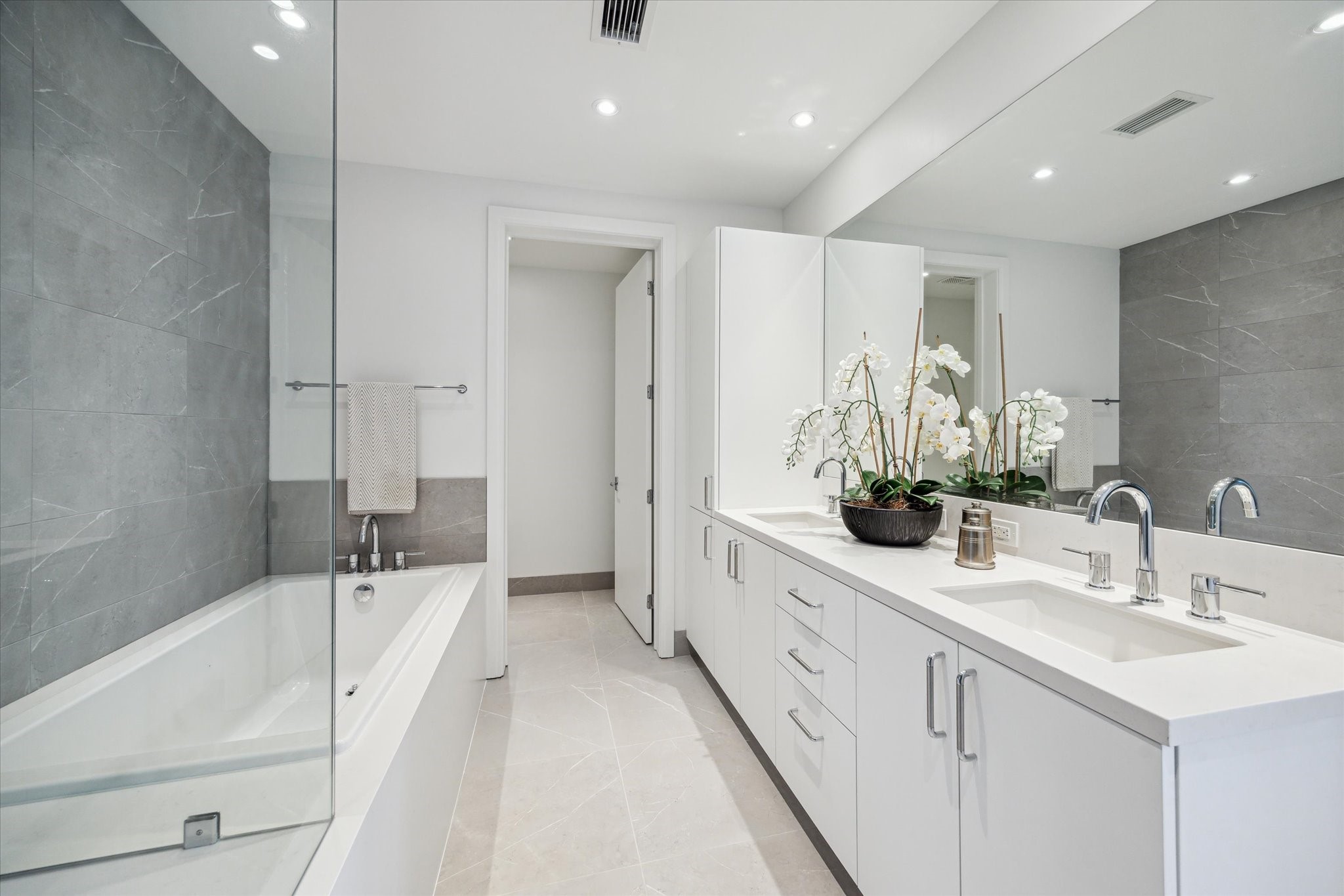 2323 West Main Street, Unit 402 Houston, TX 77098 - Photo 12 of 30 Primary en-suite bathroom with dual vanities, soaking tub and full surround in porcelain tiles.