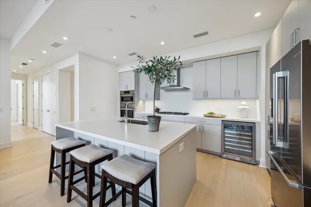 a kitchen with kitchen island a dining table chairs stainless steel appliances and cabinets