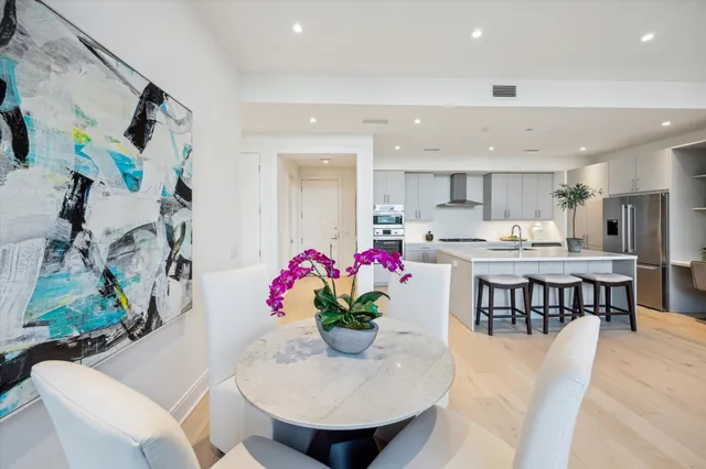 a kitchen with stainless steel appliances kitchen island granite countertop a dining table chairs and a sink