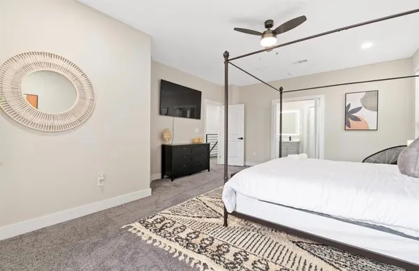 a spacious bedroom with a large bed a flat tv screen and a closet