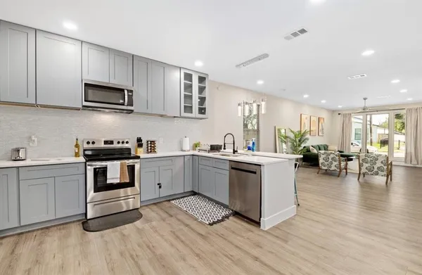 a kitchen with a sink wooden floor and stainless steel appliances