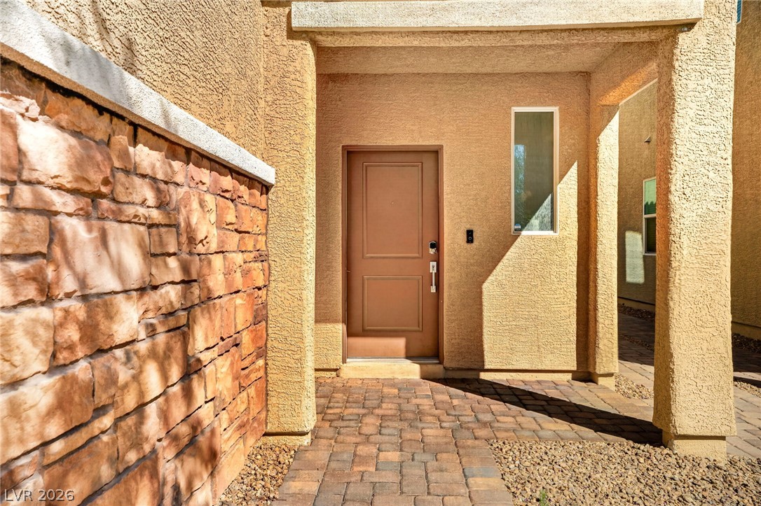 6281 Angora Peak Lane Las Vegas, NV 89115 - Photo 4 of 34 A welcoming entry features a stone accent wall and a brick paver pathway.