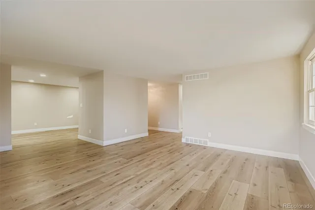 a view of an empty room with wooden floor and closet