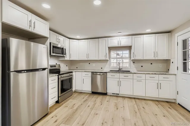 a kitchen with granite countertop white cabinets and stainless steel appliances