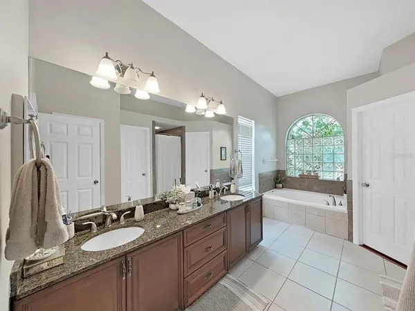 a bathroom with a granite countertop bathtub a double vanity sink a mirror a bathtub and shower