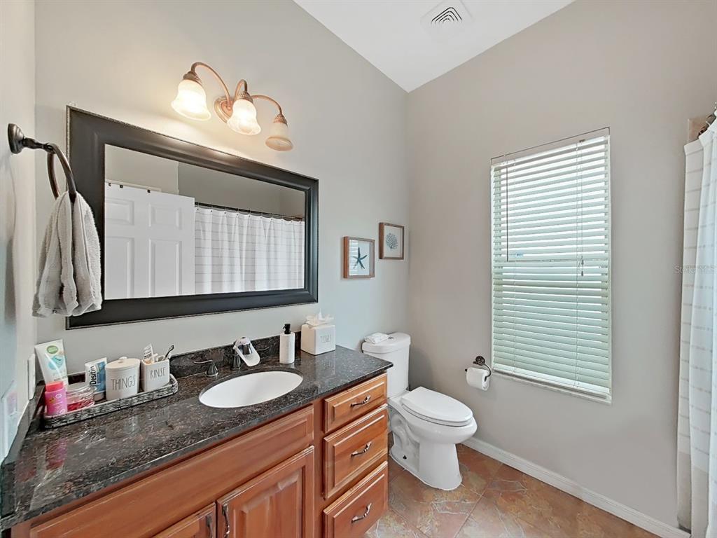 9630 Fox Hearst Road Tampa, FL 33647 - Photo 34 of 47 a bathroom with a granite countertop sink toilet a mirror and a window