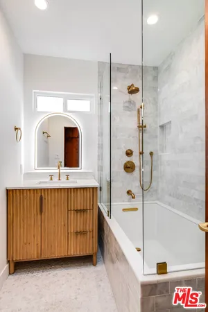 a bathroom with a tub a double vanity sink and mirror