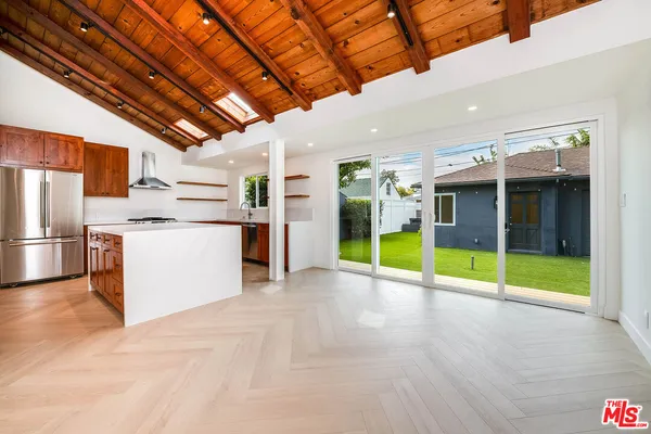 a view of an empty room with kitchen view and a fireplace