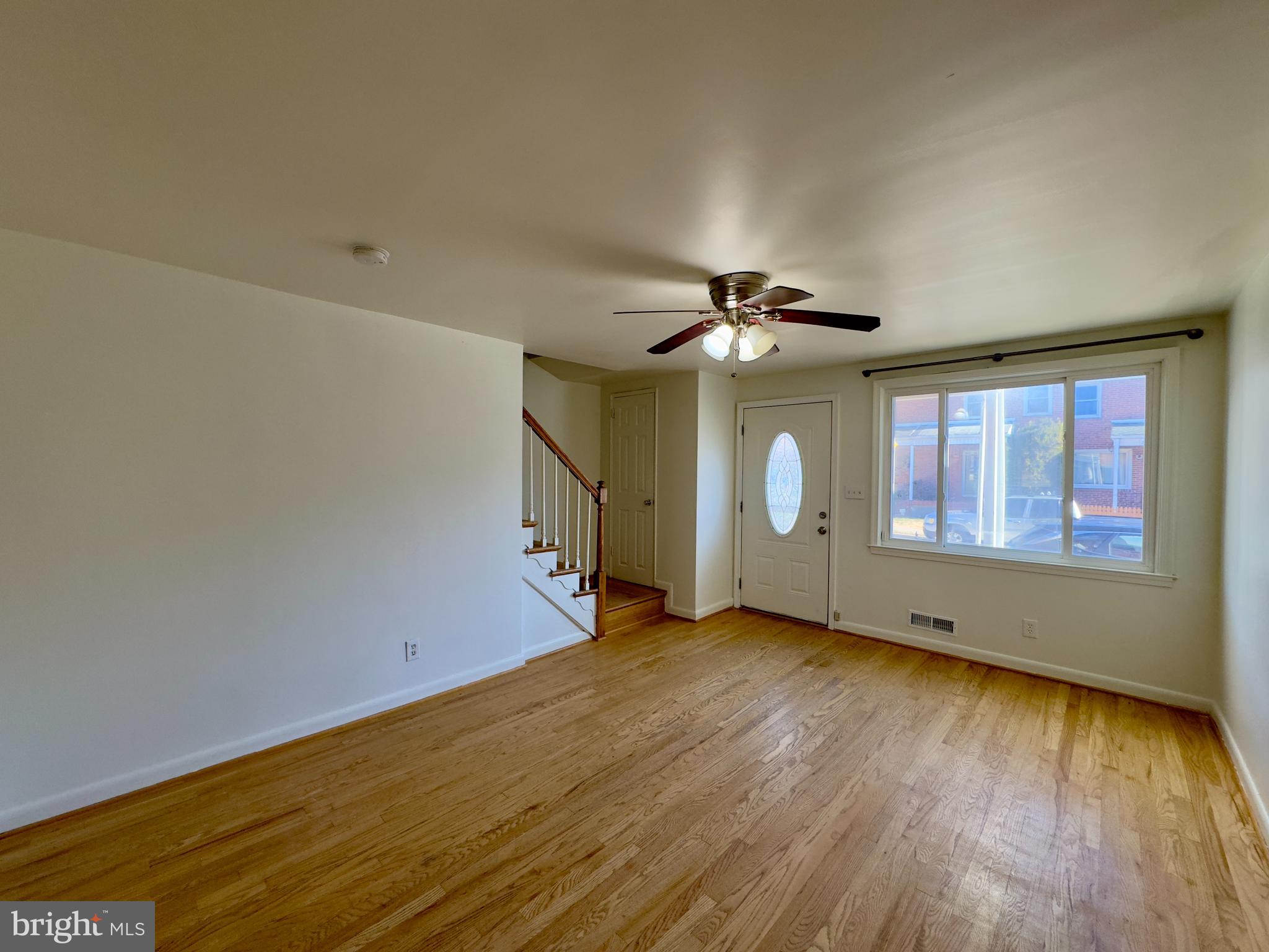 512 Umbra Street Baltimore, MD 21224 - Photo 2 of 20 an empty room with wooden floor chandelier fan and windows
