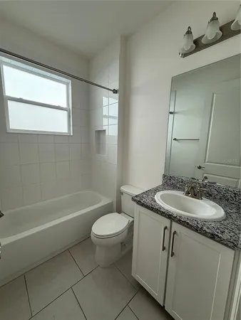 a bathroom with a granite countertop sink toilet a mirror and bathtub