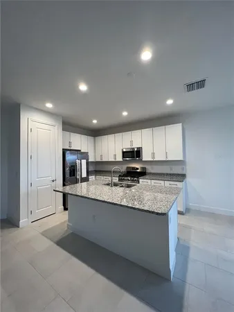 a large kitchen with kitchen island a sink a center island stainless steel appliances and a cabinets