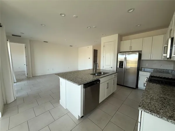 a kitchen with stainless steel appliances granite countertop a stove a sink and a refrigerator