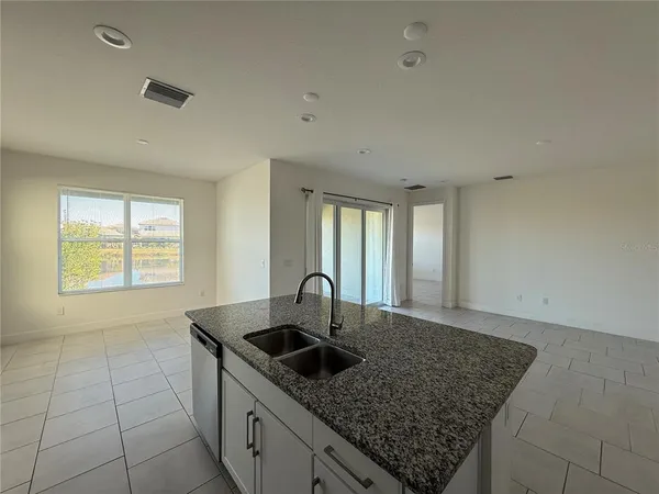 a kitchen with granite countertop a sink window and cabinets
