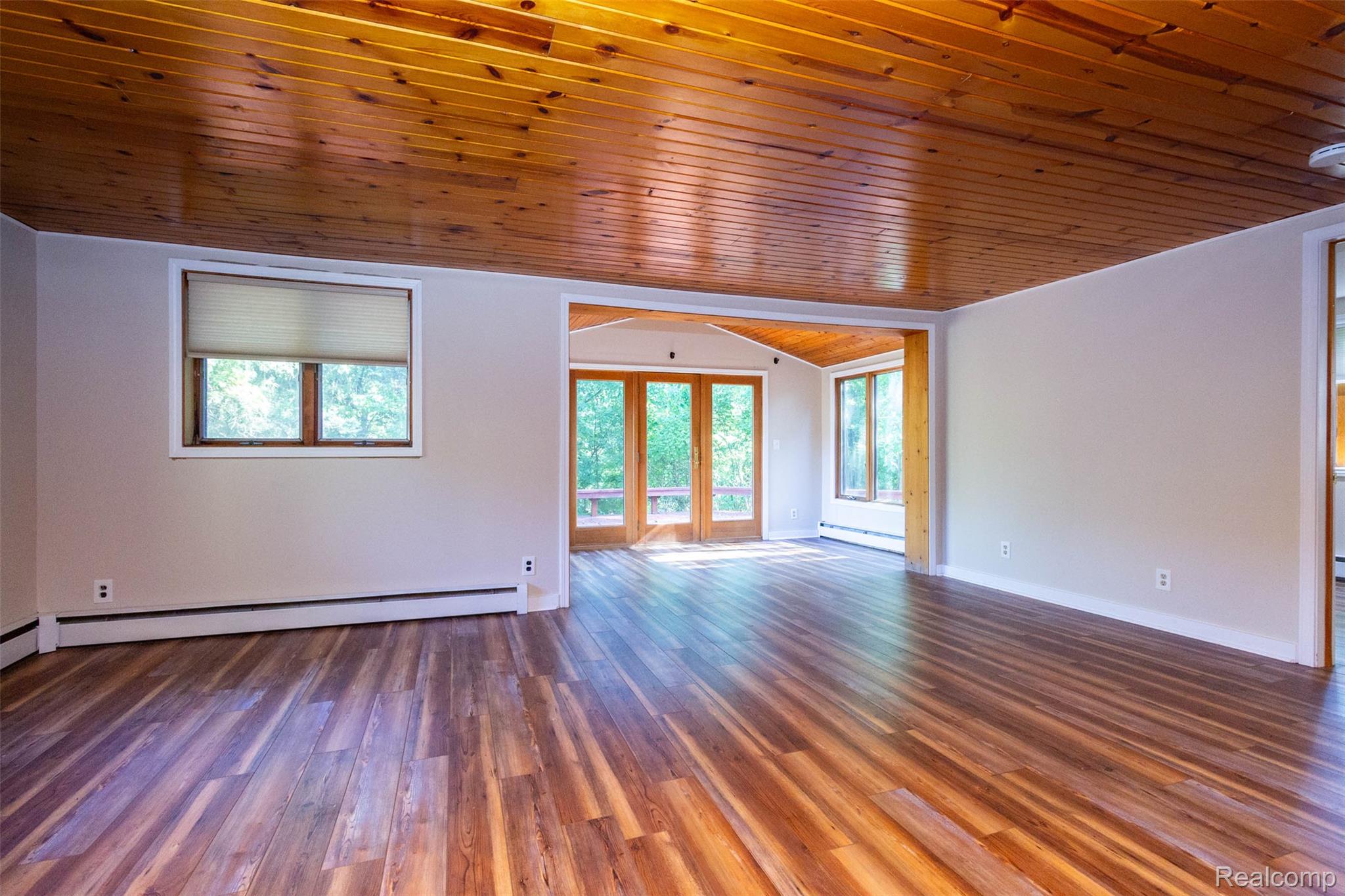 14044 Ridgemont Drive Gregory, MI 48137 - Photo 7 of 33 Wood-finish plank flooring, wood panel ceiling, neutral wall paint, and multiple windows