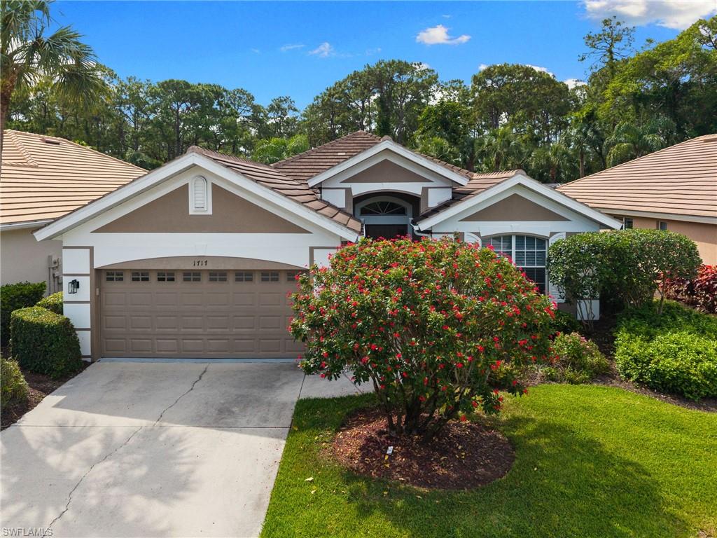 1717 Winding Oaks Way Naples, FL 34109 - Photo 1 of 29 a front view of a house with a garden