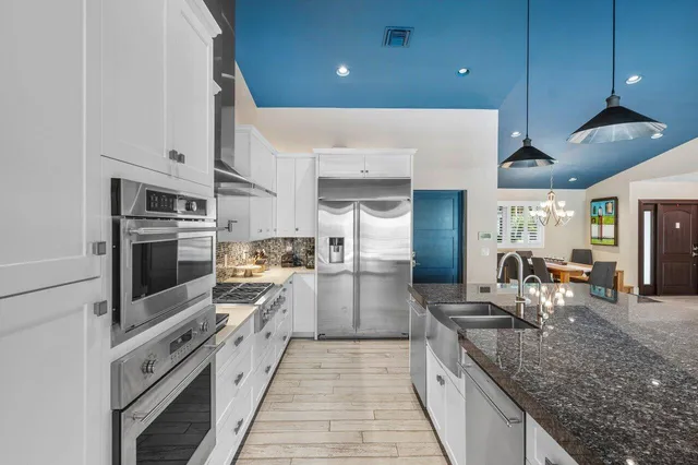 a kitchen with stainless steel appliances granite countertop a sink and a wooden floors