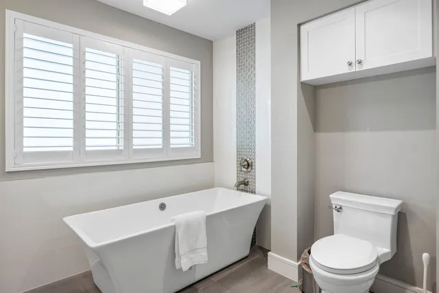 a bathroom with a granite countertop mirror vanity and toilet