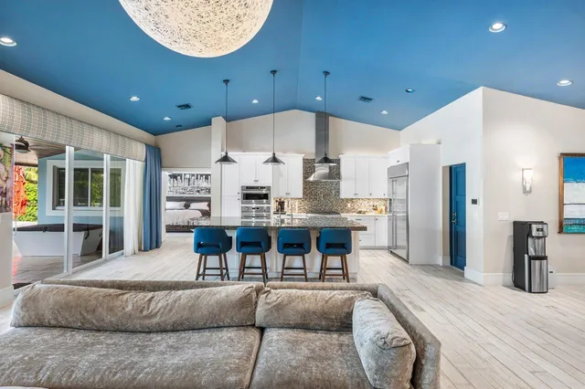 a kitchen with stainless steel appliances kitchen island granite countertop a table chairs sink and cabinets