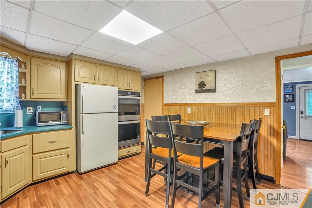 141 Old Road Sewaren, NJ 07077 - Photo 5 of 30 a kitchen with stainless steel appliances a refrigerator a stove a dining table and chairs with wooden floor