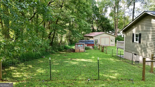 a view of a house with a yard plants and large tree