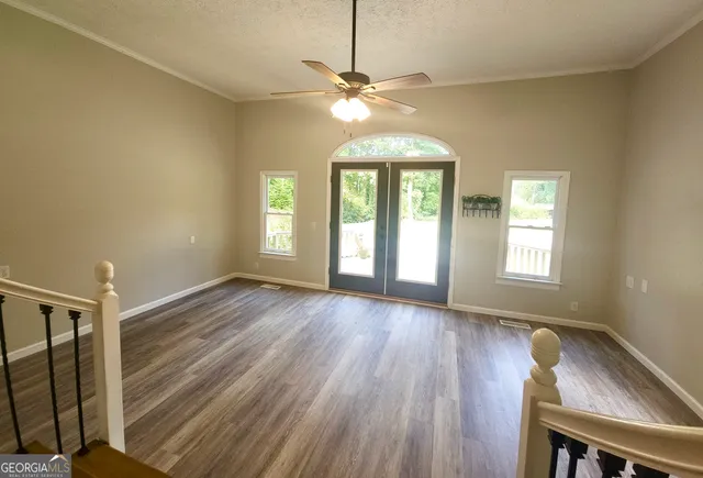 a view of an empty room with wooden floor and a window