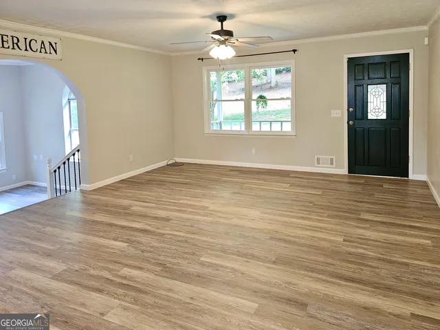 an empty room with wooden floor chandelier and windows