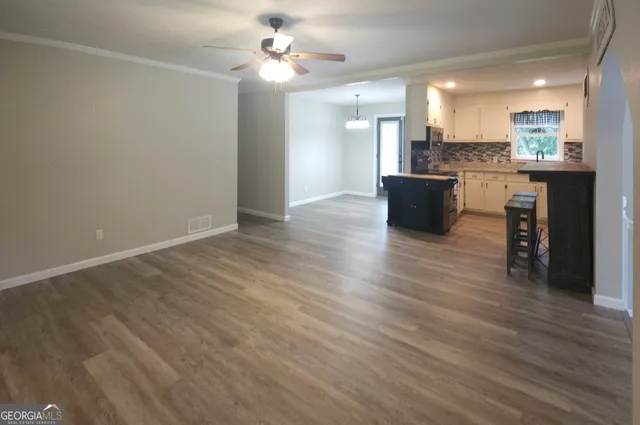 a large room with wooden floor and a kitchen view
