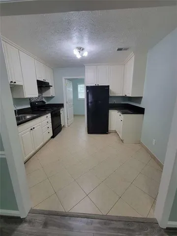 a large white kitchen with a refrigerator a stove a microwave and cabinets