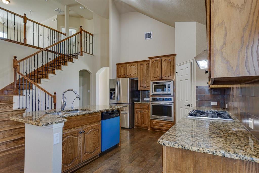 1522 Blue Jay Road Garland, TX 75043 - Photo 14 of 32 Open concept kitchen featuring granite countertops, wood-finish flooring, and stainless steel appliances
