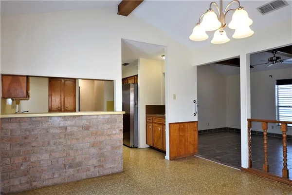 a view of an empty room with window and a kitchen