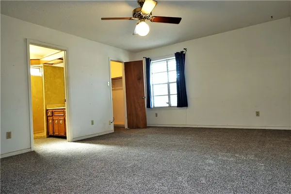 an empty room with windows and fan