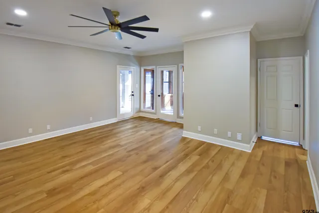 an empty room with wooden floor and windows