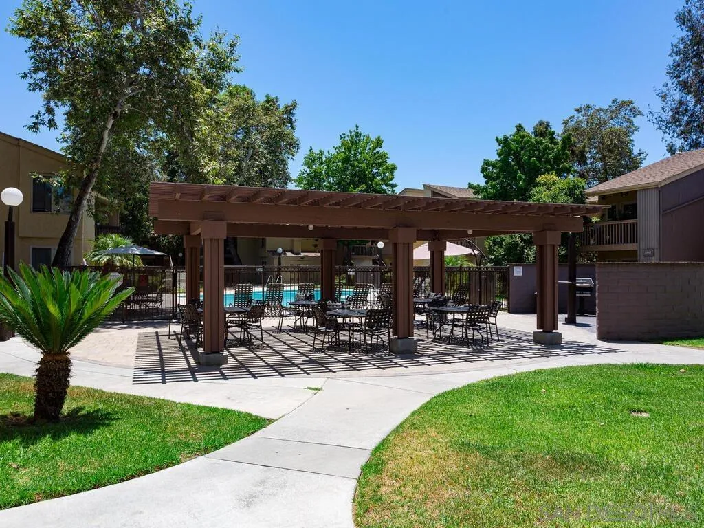 5950 Rancho Mission Road, Unit 166 San Diego, CA 92108 - Photo 8 of 18 a view of a patio with table and chairs under an umbrella
